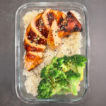 Gesunde Miso Power Bowl mit gebratenem Hähnchen in Miso-Marinade, grünem Brokkoli und Sushireis als vorbereitetes Mittagessen.