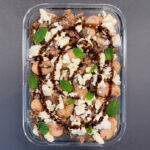 Frischer Protein-Salat aus Riesenbohnen, Linsen und Thunfisch in einer Schüssel, garniert mit zerbröseltem Feta, roten Zwiebeln und frischer Minze.